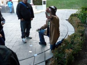 A Three Card Monte dealer takes a break and waves at the camera.